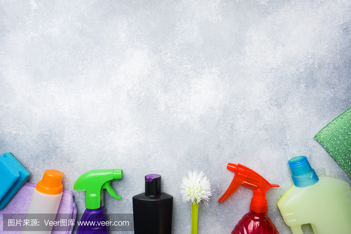 瓶子與洗滌劑,刷子和海綿在混凝土背景。色彩鮮艷的清潔產品。家庭清潔的概念。俯視圖,復制空間。